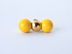 A head-on detail shot of the same brass and yellow double-ball knob, showing the finish and proportions clearly before installing it. Useful for checking scale and color against your own cabinetry.