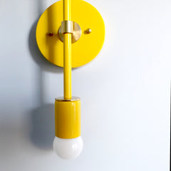 right yellow and brass Medium Thalia Sconce with double globe bulbs, bold color-pop mid century modern wall sconce in a vibrant color-drenched palette, modern vertical wall light with round backplate, perfect for maximalist interiors, kids room lighting, playful nursery decor, sunny hallway wall light, or statement bathroom vanity lighting by Sazerac Stitches