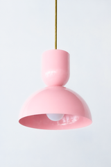 Pink is the easiest way to give a kitchen or nook a little personality without going loud, and this Taeuber pendant does it with real mid-century polish. The sculptural silhouette pairs a rounded cup top with a wide domed bell, finished in a soft glossy blush and hung from a warm brass stem. It reads sweet but grown-up, at home over an island, a bar, a breakfast table, or even a bedside. Cluster a few or let one stand alone as a gentle pop of color. A charming pick for a colorful, feminine-leaning home that