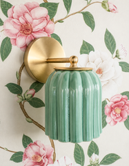 Pink and white camellias trail across this Chinoiserie wallpaper on winding painted branches, and the Marcella Sconce in Jade Green tucks right into the greenery, its glossy fluted shade echoing the leaves rather than competing with the blooms. A soft, botanical pairing for grandmillennial bathrooms, powder rooms, and bedrooms that want floral wallpaper with real depth and classic charm.