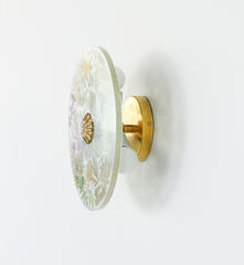 Side View of Botanical Wall Light – A profile shot of a brass and glass wall sconce with intricate pressed foliage designs and a translucent surface.