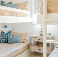 Traditional coastal beachy style bedroom with four bunk beds, beautiful mix of textiles, traditional style decor, and fun pastel blue and brass wall sconces to serve as reading lights.  Beautiful california beach style bedroom.