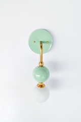 A soft pastel wall sconce for a bathroom, nursery, or bedroom that leads with calm, sweet color. The Ida sconce pairs a glossy mint powder-coated sphere with a frosted glass globe, joined by warm brass hardware and a round mint backplate. Gentle, pretty, and easy to live with, it's a standout for grandmillennial, English cottage, coastal traditional, and playful kids' spaces that skip the safe answer.