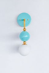 A statement wall sconce for rooms that lead with fresh, watery color. Seen in profile, the Ida sconce pairs a glossy pool-blue powder-coated sphere with a frosted glass globe, joined by warm brass hardware and a round aqua backplate. Airy, calm, and quietly cheerful, it's a spirited pick for coastal bathrooms, powder rooms, nurseries, and Southern traditional rooms that want one breezy, standout detail.