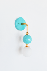 A soft aqua wall sconce for a bathroom, nursery, or coastal bedroom that leads with fresh, calming color. The Ida sconce pairs a glossy pool-blue powder-coated sphere with a frosted glass globe, joined by warm brass hardware and a round aqua backplate. Breezy, airy, and easy to live with, it's a standout for coastal traditional, grandmillennial, Chinoiserie, and playful kids' spaces that skip the safe answer.