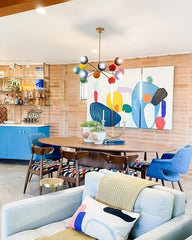 Prism Chandelier in a mid-century modern dining room with colorful abstract wall art, wood furniture, and bold blue accents. A rainbow sputnik ceiling light fixture adds vibrant dopamine décor energy, blending eclectic style with retro-inspired design for creative, modern homes.