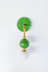 Fresh, cheerful vanity lighting that gives a bathroom or powder room real personality. Seen in profile, the Ida sconce shows off its curved brass arm reaching from a glossy grass-green backplate down to a stacked green sphere and frosted glass globe. The side view highlights the brass ball detailing and how far the fixture projects off the wall. A lively, garden-inspired choice for colorful traditional, English garden, and grandmillennial interiors.