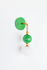 A statement wall sconce for rooms that lead with fresh, lively color. This angle of the Ida sconce puts the bold round grass-green backplate front and center, with a brass arm curving down to a glossy green sphere and frosted glass globe. Bright, garden-fresh, and cheerful, it's a spirited pick for colorful bathrooms, powder rooms, kids' spaces, and maximalist rooms that want one joyful, standout detail.