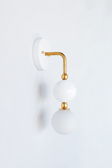 A statement wall sconce for rooms that want a clean neutral warmed with brass. Seen in profile, the Ida sconce pairs a glossy white powder-coated sphere with a frosted glass globe, joined by warm brass hardware and a round white backplate. Soft, timeless, and quietly confident, it's a versatile pick for bathrooms, powder rooms, bedrooms, and transitional spaces that want one clean, standout detail.