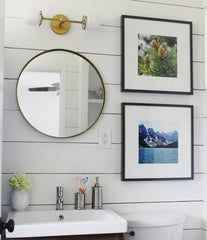 Mixing brass and black in a bathroom remodel with shiplap walls and a circular mirror