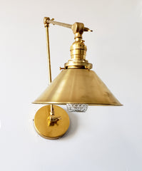 all brass industrial style sconce with a cone shade and adjustable arms perfect for open shelving