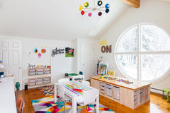 Rainbow themed playroom with crafting station, table, bins, and a big window with natural light