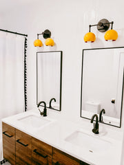 Mid Century Modern bathroom with mustard and black wall sconces and wood vanity