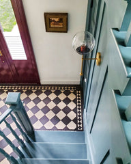 Traditional style staircase in an old home.  Features black and white checkerboard floors, stairs painted a shade of teal, and a brass wall sconce made by Sazerac Stitches.