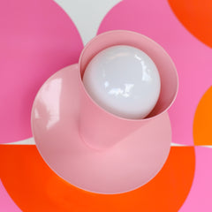 light pink wall sconce or ceiling light fixture on a retro orange and pink wallpaper design