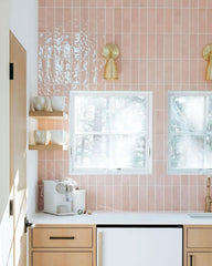 Brass michoud sconces on stacked blush-colored subway tile in a kitchen with natural wood cabinets