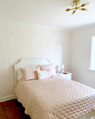 pale pink wallpaper with white furniture and a white headboard and nightstand