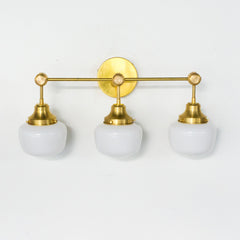 Brass three-light Schoolhouse glass bathroom wall sconce