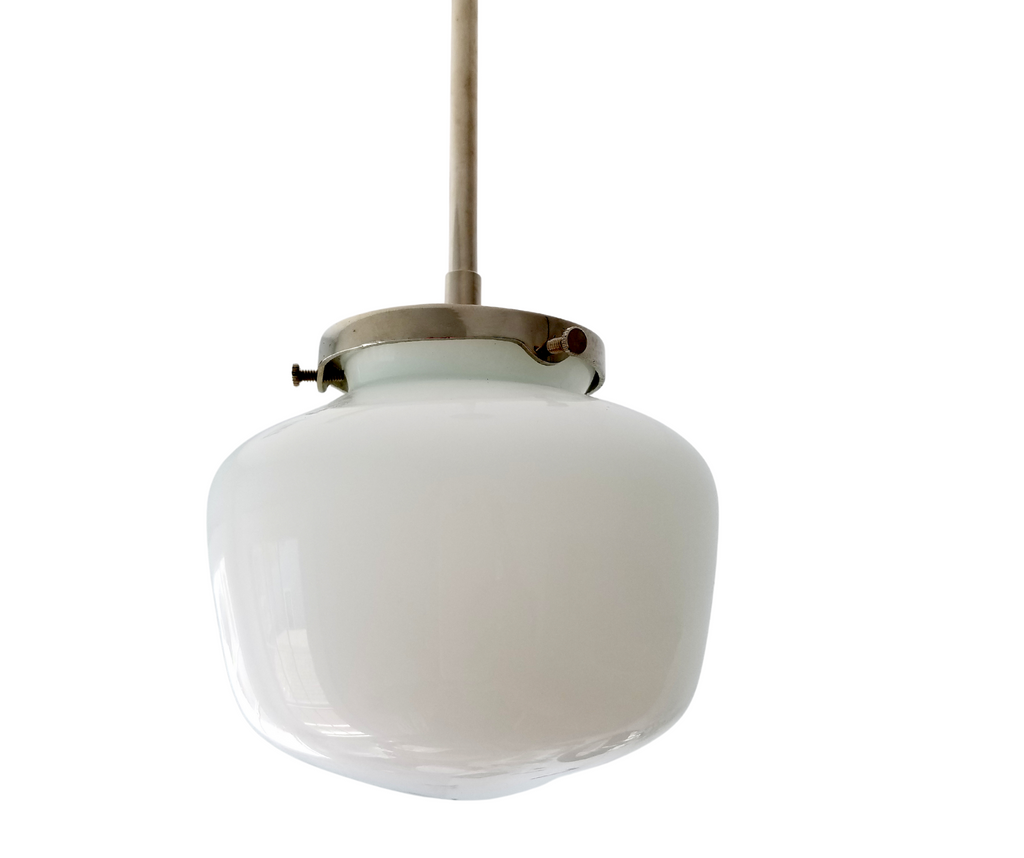 Imagine a kitchen that whispers rather than shouts—where clean lines meet warmth, and every fixture earns its place through quiet confidence. This is where a schoolhouse pendant belongs: the gently rounded, compressed dome of the shade creates a sculptural presence that feels both architectural and approachable. Brushed nickel hardware pairs the glass with contemporary restraint, letting the utilitarian elegance of the form take center stage. The wide opening floods light downward, perfect for counters and 