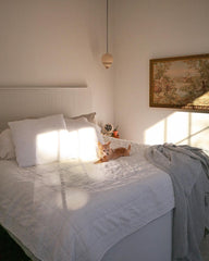 Bedroom makeover with cream nesting loa pendants in an offwhite room with antique art