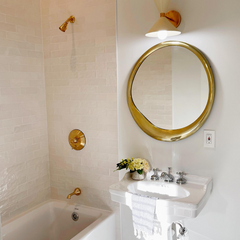 Neutral bathroom design with a chunky gold mirror and traditional style details