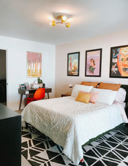Graphic bedroom with black and white rug, vintage posters, and a crisp white bed.  Boho bedroom vibes
