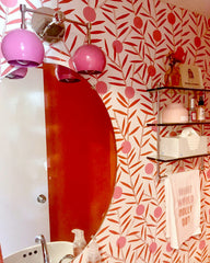 Pink and red bathroom design featuring midcentury modern inspired two light sconce