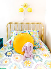 children's bedroom with a wood headboard, handmade quilt, and a yellow double loa sconce