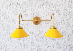 Yellow and Brass two light modern wall sconce on female wallpaper