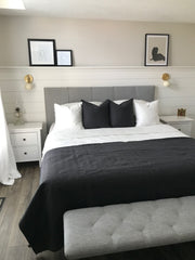 Monochromatic Grey and Cream Bedroom with Grey upholstered headboard, cream and brass wall sconces, and white shiplap