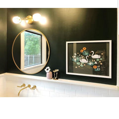 West End Sconce above a circular mirror on a dark green walls with wainscotting