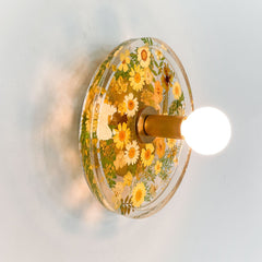 Yellow Botanico sconce lit up.  Resin and brass floral wall sconce made by Sazerac Stitches