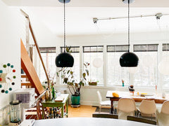 Large Neutral Loft area with white walls, natural wood floors, black globe pendants, and lots of natural light