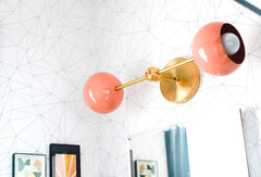 modern wall sconce with geometric  white and black wallpaper and a peach and brass sconce