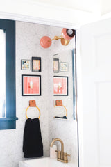 Modern bathroom renovation with geometric wallpaper and peach and brass wall sconce