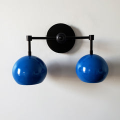 blue and black two light midcentury modern inspired wall sconce lighting with globe shades.  Fun colorful lighting for bathroom renovations.