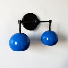 blue and black two light midcentury modern inspired wall sconce lighting with globe shades.  Fun colorful lighting for bathroom renovations.
