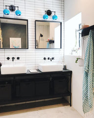 mid century modern bathroom with black cabinets and black and blue wall sconces