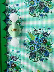 Mint and brass sconce on floral check wallpaper in a bold colorful bathroom