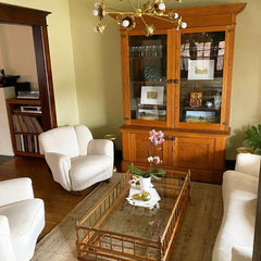 traditional style living room with white sofa and chairs, brass floral sputnik chandelier, wooden chinoiserie style coffee table, and a large wood and glass display cabinet