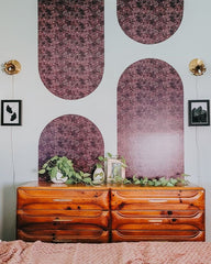 boho style bedroom with wallpaper arch installation, vintage wood dresser, trailing plant, and floral brass sconces made by sazerac stitches in New Orleans