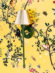 Olive green and brass wall sconce on a yellow monkey print wallpaper