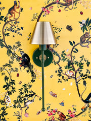 Olive green and brass wall sconce on a yellow monkey print wallpaper