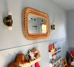 Kids room or nursery featuring light blue scalloped walls, a natural wood rattan mirror, and marbled green and black wall sconces