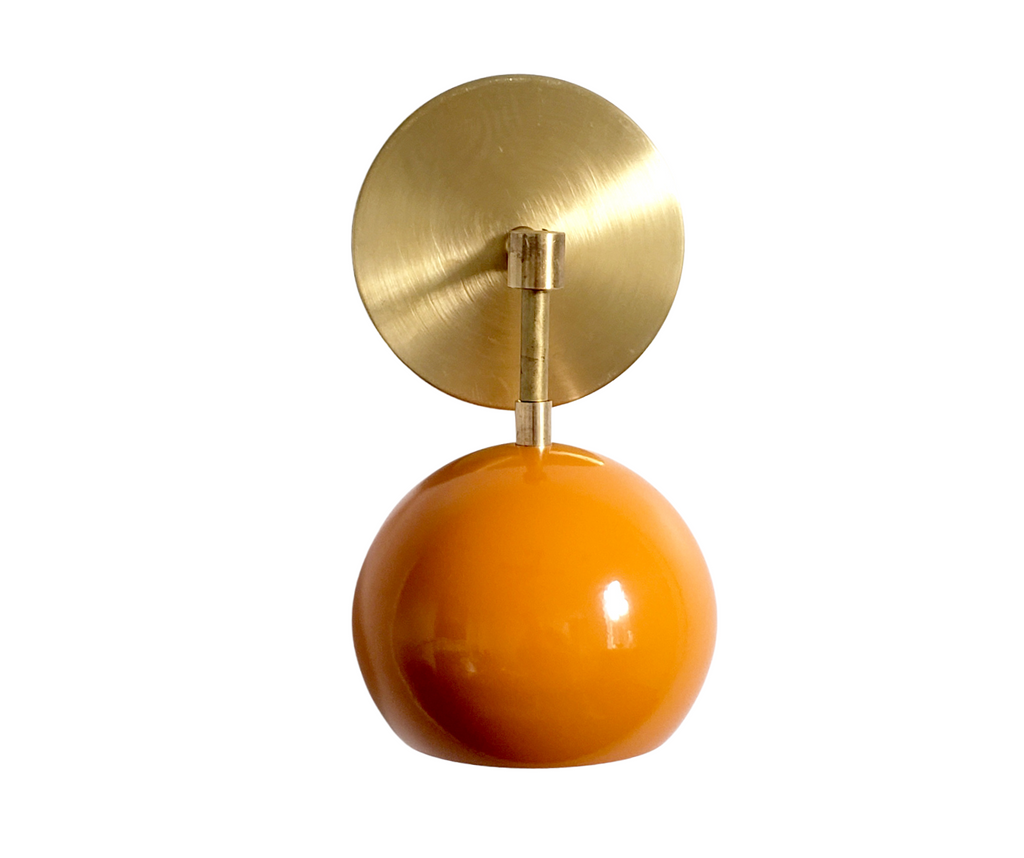 orange and brass mid century modern wall sconce with background removed
