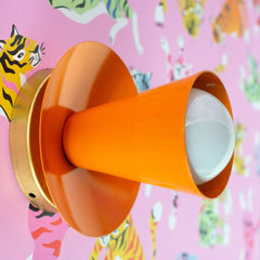 bright orange wall sconce on colorful pink wallpaper with tigers and leopards in rainbow colors