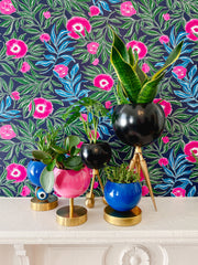 Bright pink, Bright blue, and black Loa planter trio against floral blue, green, and pink floral wallpaper