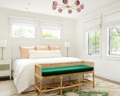 Neutral bedroom with hints of pink, peach, and green with white roman curtains and a traditional rug