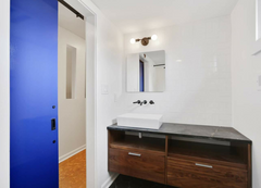 Modern white and wood bathroom with a bold klein blue door