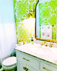Brass Loa sconce in a pink and green bathroom remodel with green wallpapered walls